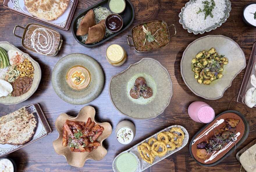 Overview of multiple Indian dishes on a wooden table.