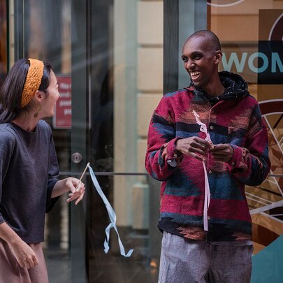 Two people sharing a laugh while holding little sticks with steamers. 
