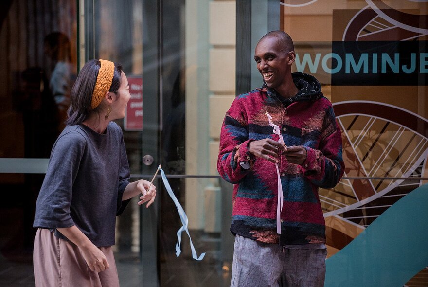 Two people sharing a laugh while holding little sticks with steamers. 