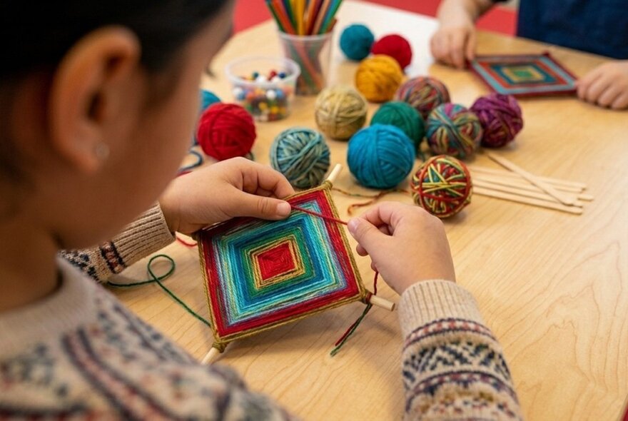Children using wool to create triangular woven crafts with balls of wool.