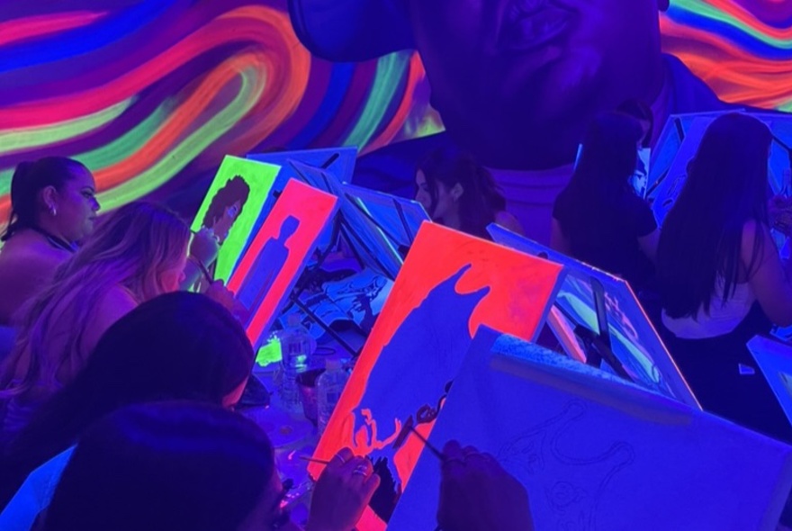 People painting in a glow in the dark room with swirling colours.