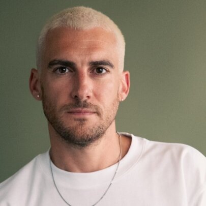 Josh Silver, with beard and silver dyed hair, wearing a white T-shirt.