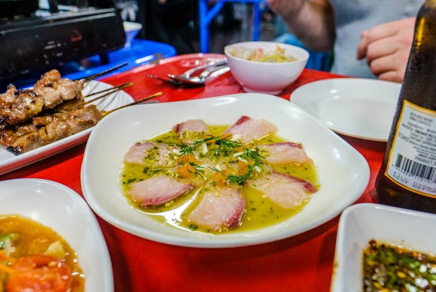 Various plates of Thai dishes on a red table.