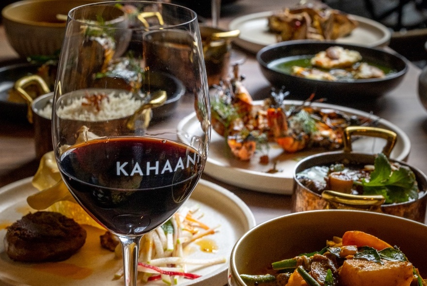 A table with dishes of food and glass of red wine.