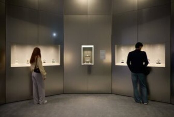 People looking at exhibit cabinets in an exhibition setting.