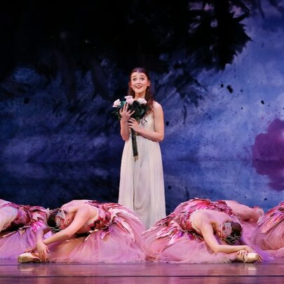 A young girl stands on stage with fallen ballerinas all around her in a production of The Nutcracker. 