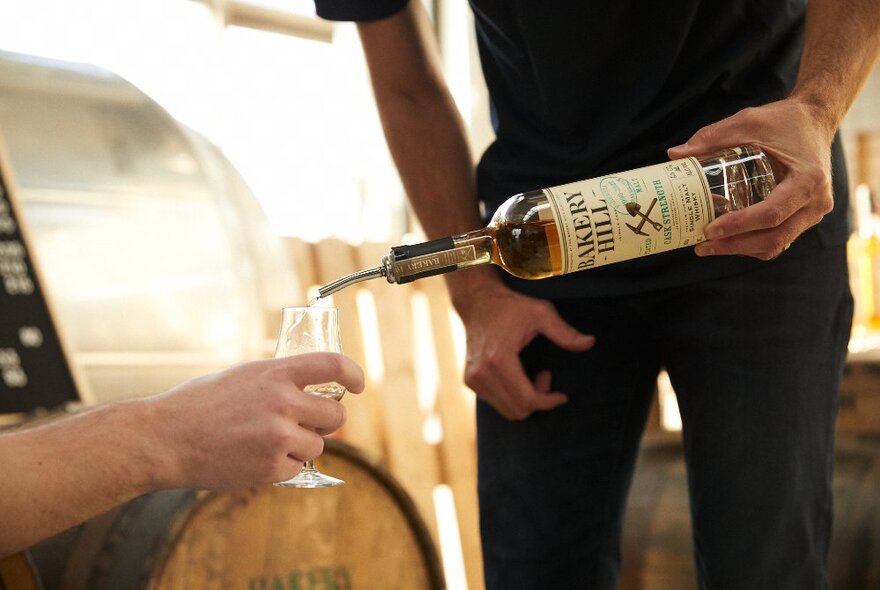 A server pouring whisky from a bottle into a customer's glass.