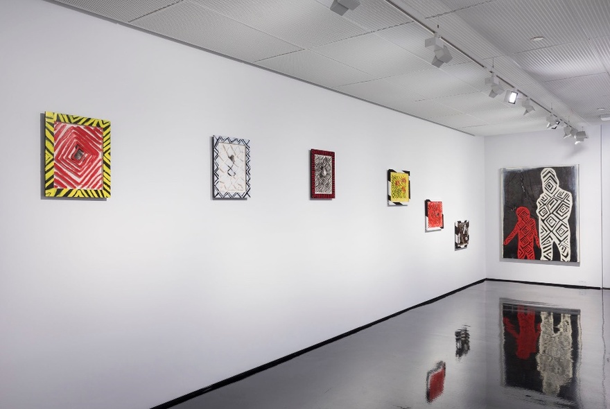 Installation view of an exhibition of paintings hanging on the walls inside a gallery.