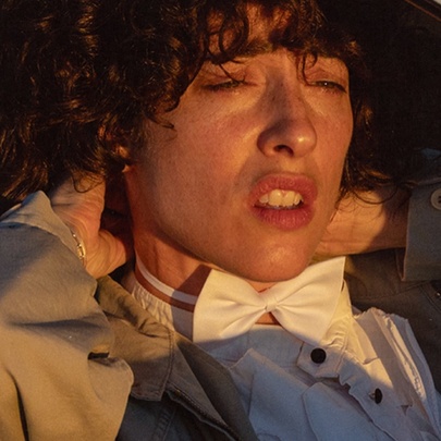 Comedian Hannah Camilleri wearing a white bowtie, looking pained. 