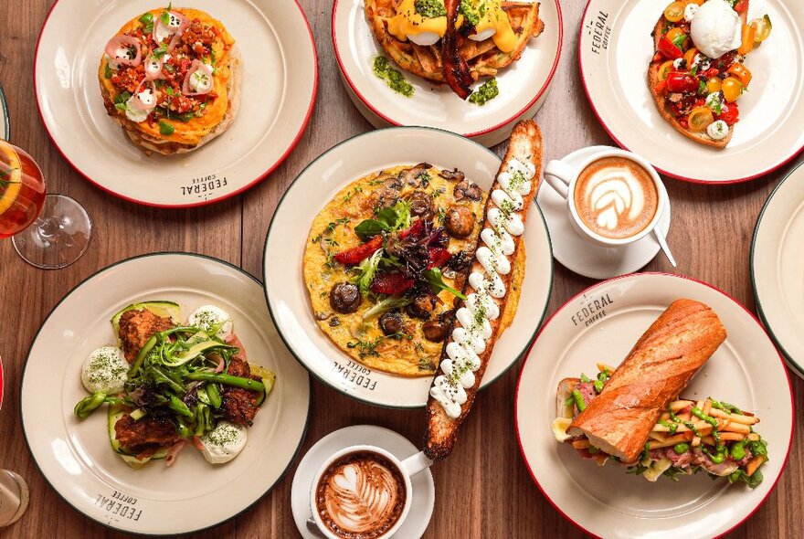 Tasty brunch options laid out on plates on a wooden table with two cofees and a champagne glass with cocktail.