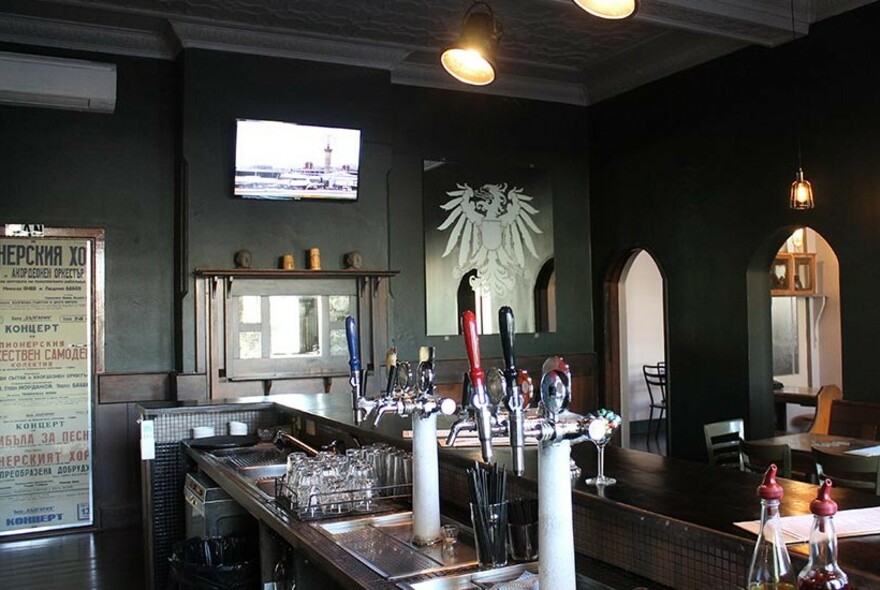 Pub counter with beer taps and glasses, looking over to dining room tables and chairs.