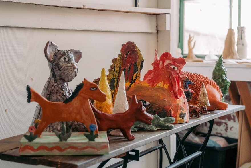 Coloured sculptures of animals on a table, including a cat and horse.