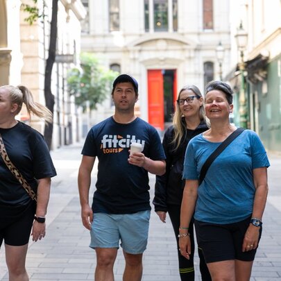 Three people on a walking tour with a Fit City tour guide, two carrying a takeaway coffee.