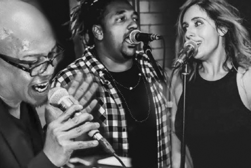 Two men and one woman, all singing into microphones; black and white photo.