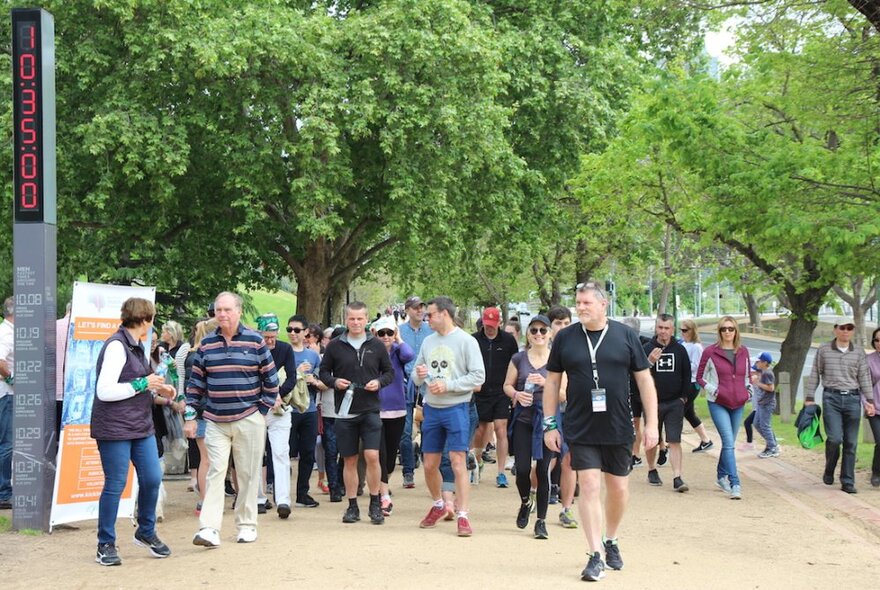 A crowd of people walking along the Tan Track in Melbourne's Botanical Gardens.