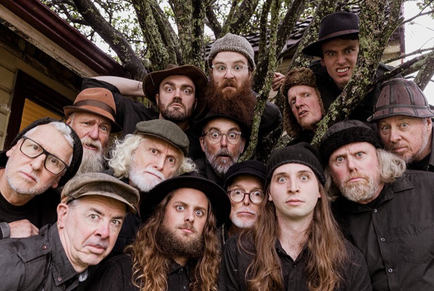 Large group of men of varied ages, many with beards and long hair, wearing hats.