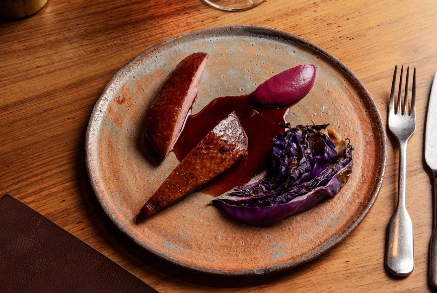 Cutlery and plate of meat with gravy.