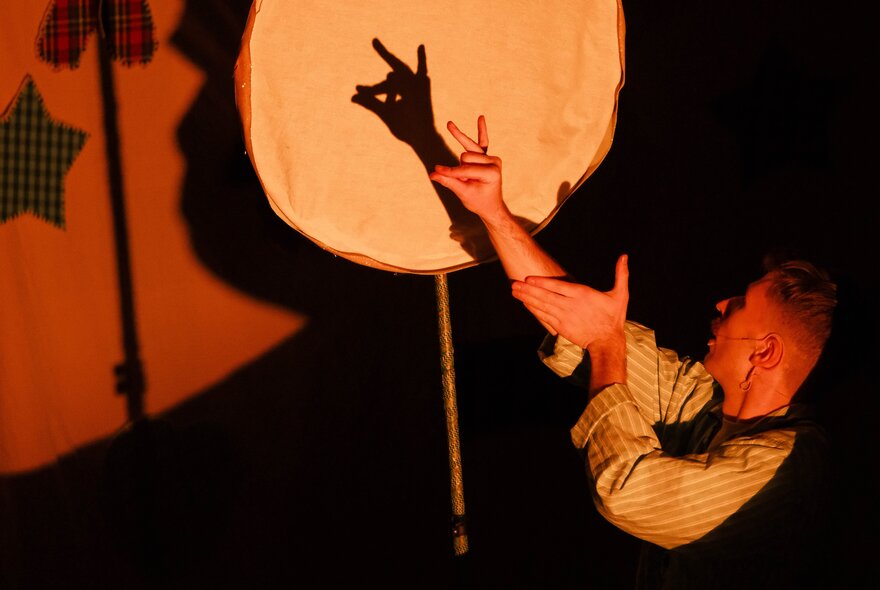 A person creating a shadow puppet of a dog.