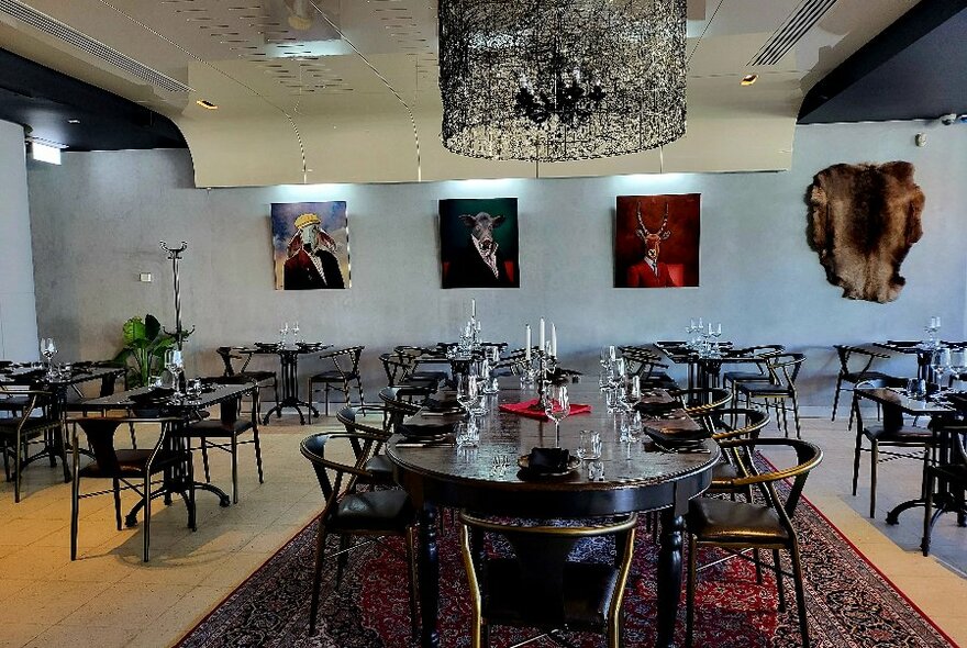 Restaurant interior with tables set for dining and paintings on the wall.