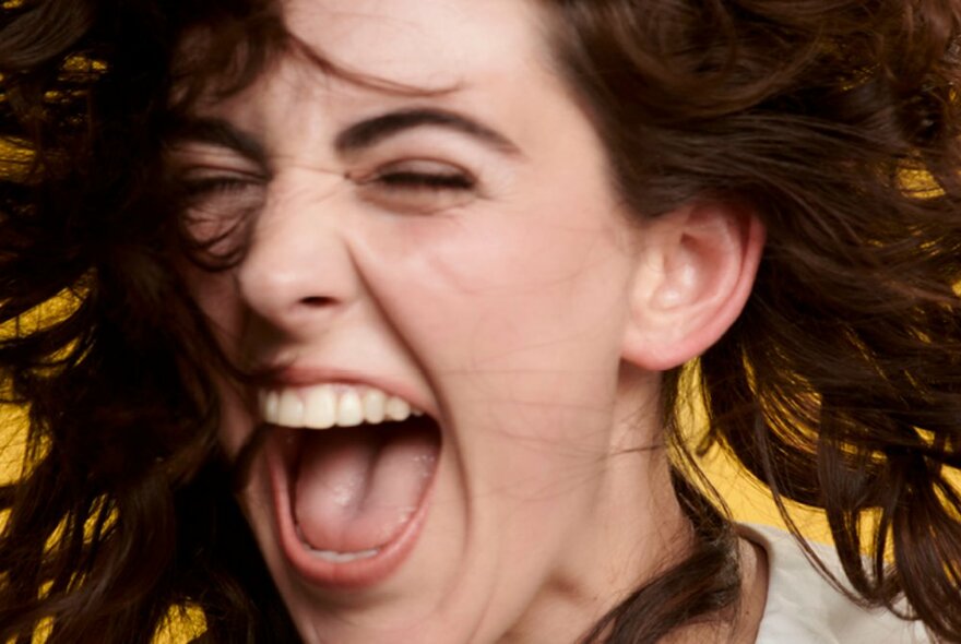 Close-up of the face of actress Kala Gare, her eyes closed, her mouth open as if singing and her hair swirling around her face.