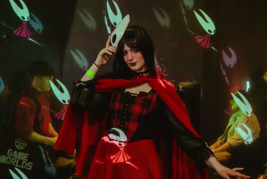 A still from a video game showing a woman in a red and black caped outfit.