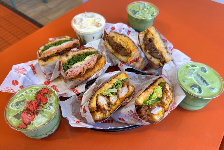 A table with three large toasties and matcha drinks on it