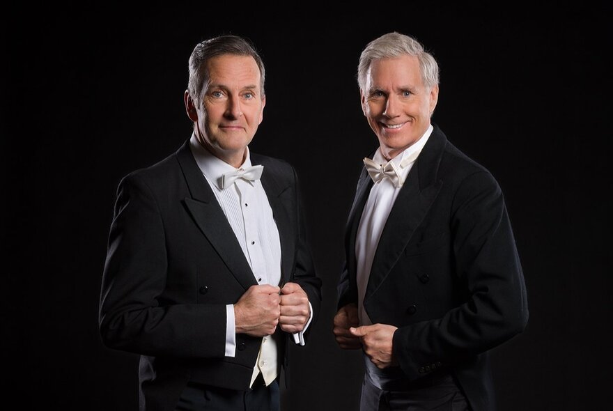 Comedian Colin Lane and opera singer David Hobson, both wearing black tuxedos with tails and white bowties.