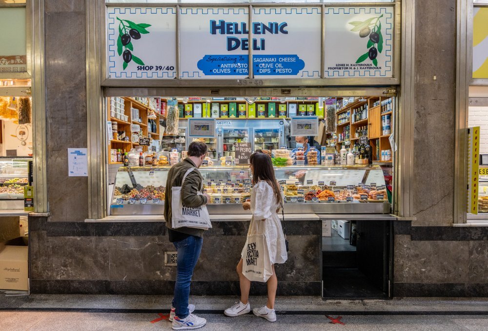 A couple shopping at a Greek deli inside a market.