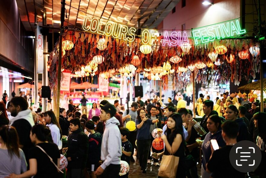 An Asian-style night market with a large crowd of people.