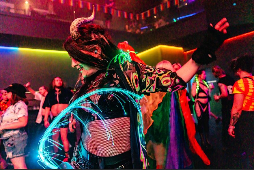 Person dressed in cosplay outfit with blue neon swirls.