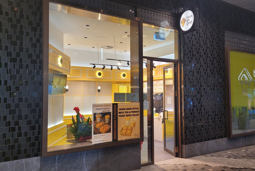 The exterior of Toast Go Gold at night with lights on inside and an illuminated sign. 