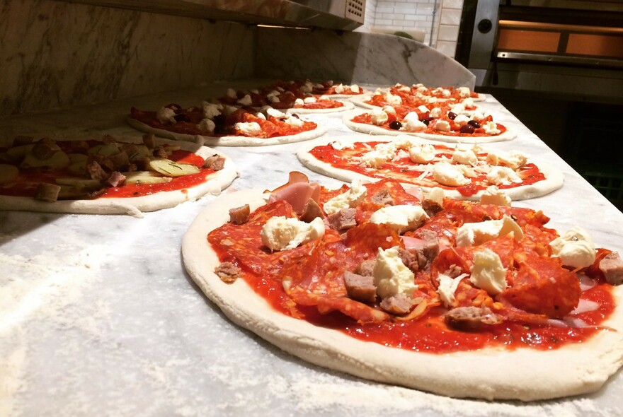 Pizza lined-up to be cooked.