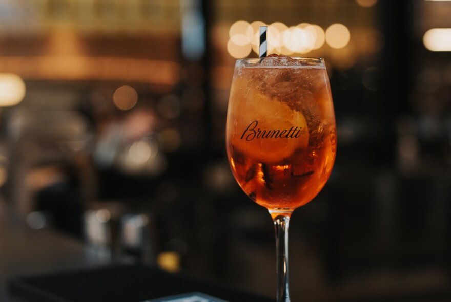 An Aperol Spritz served with ice in a glass with the words Brunetti faintly visible on the outside of the glass.