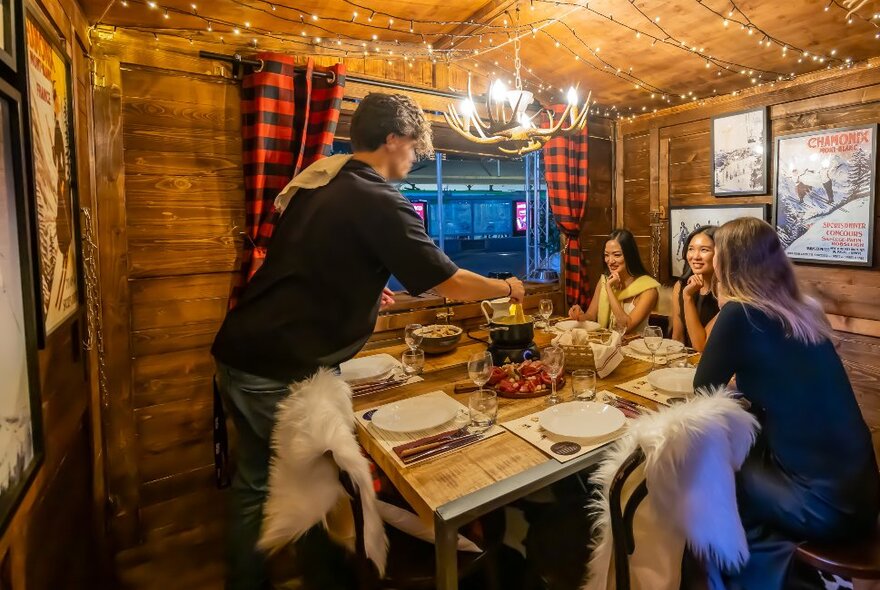 A group of friends are eating fondue in a chalet.
