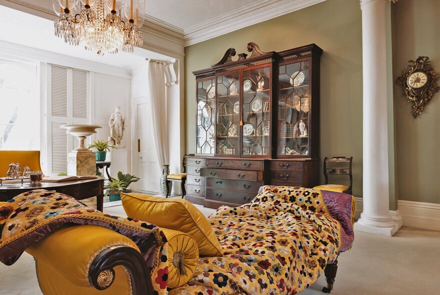 Room with Georgian pilaster and wall cabinet, chandelier and chaise-longue.