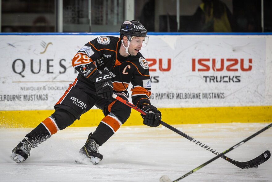 An ice hockey match with a player sliding on an angle on the ice. 