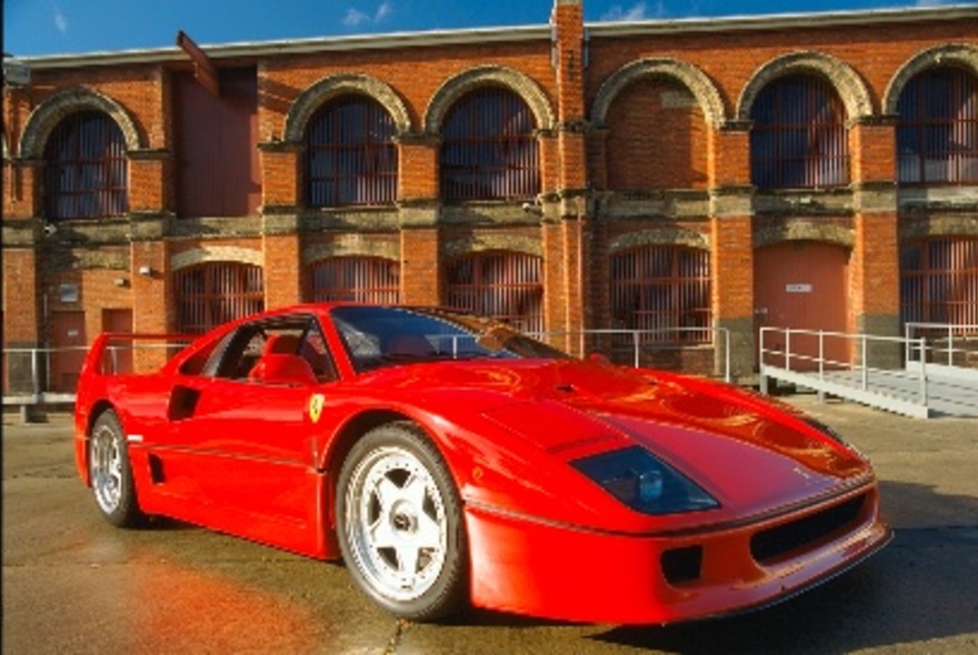 A red sports car on display in an open air space.