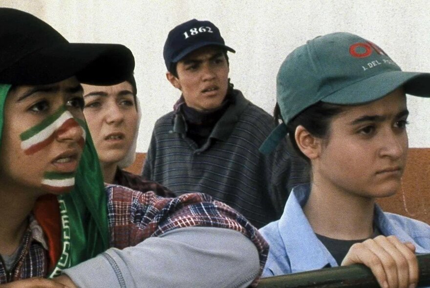 A still from an Iranian movie showing four young people looking at something with concerned expressions.