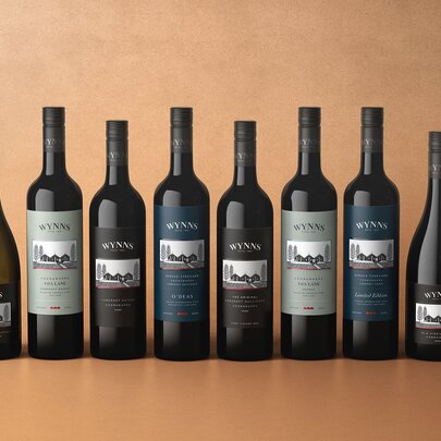 Eight bottles of Coonawarra wine lined up in a row against an orange background.