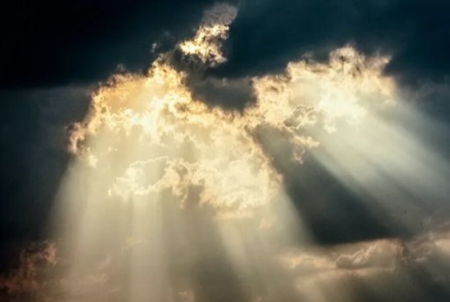Celestial sunlight pouring through dark clouds.