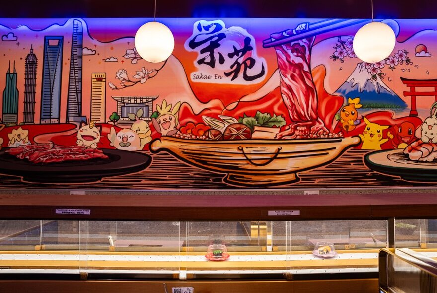 Sushi train with two dishes on an illuminated belt under Japanese wall mural.