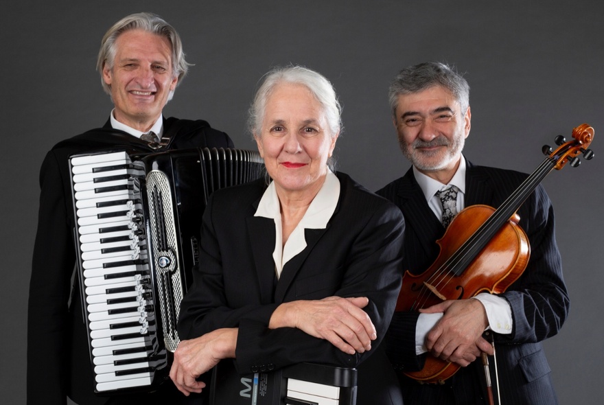 Three musicians in black, posing with their instruments.