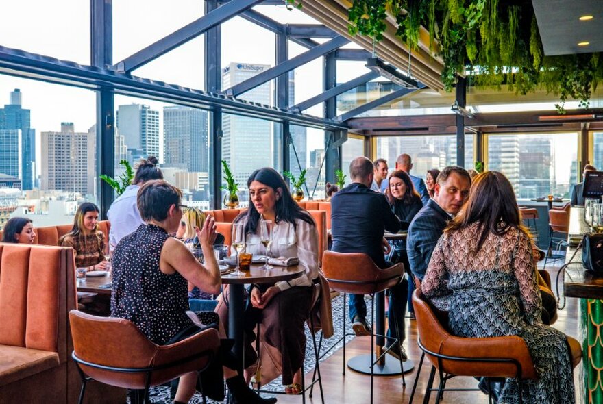 Diners in a rooftop bar overlooking the city skyline. 