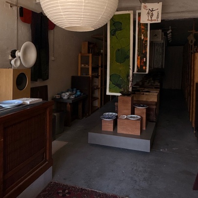 The interior of the Nordic Japan Gallery showroom with artworks displayed on the wall and tableware on  display shelves.