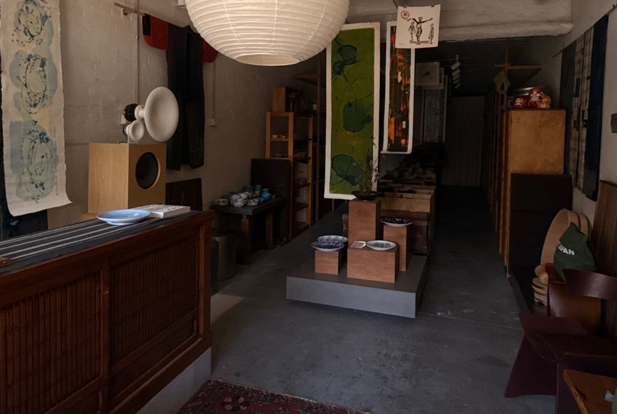 The interior of the Nordic Japan Gallery showroom with artworks displayed on the wall and tableware on  display shelves.