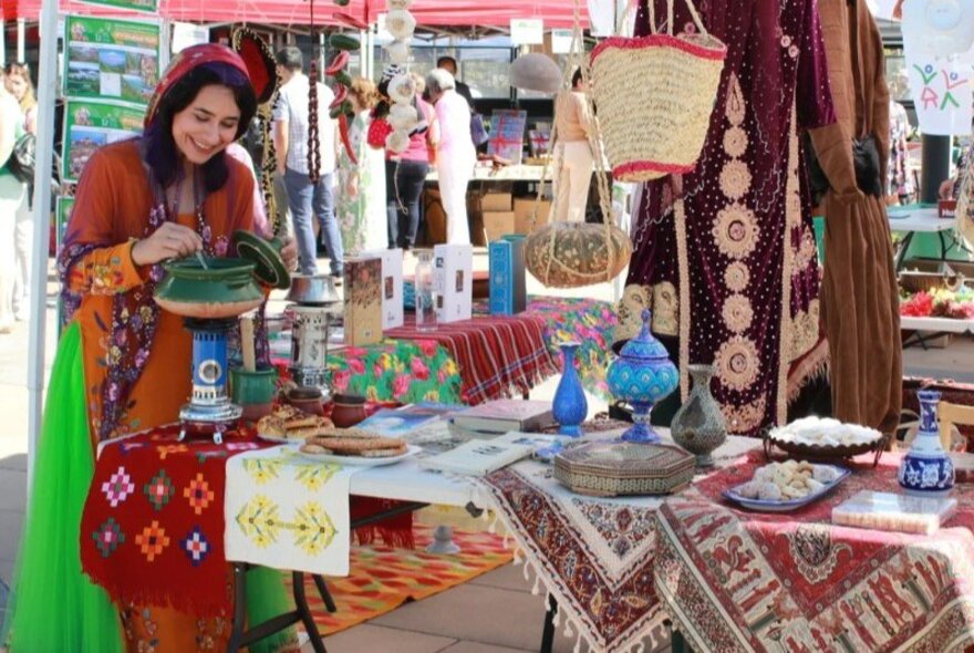 A woman of Persian heritage at a market stall with Persian goods.