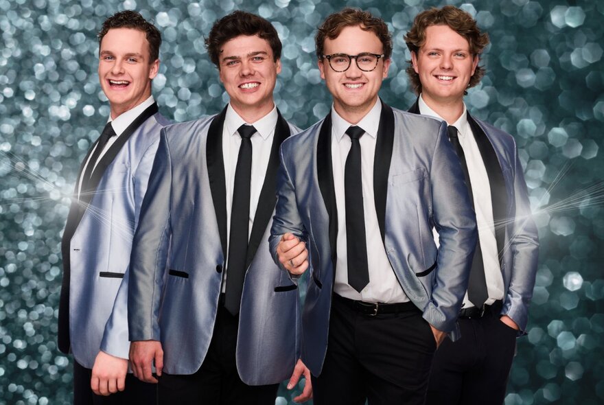 Vocal band, The 60 Four, posing in front of a sparkly background, wearing silver dinner jackets and with black lapels and black ties.