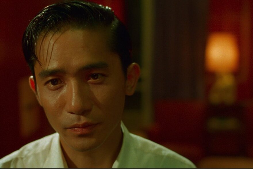 The neutral looking face of the actor Tony Leung Chiu Wai in a still from the film In the Mood for Love.