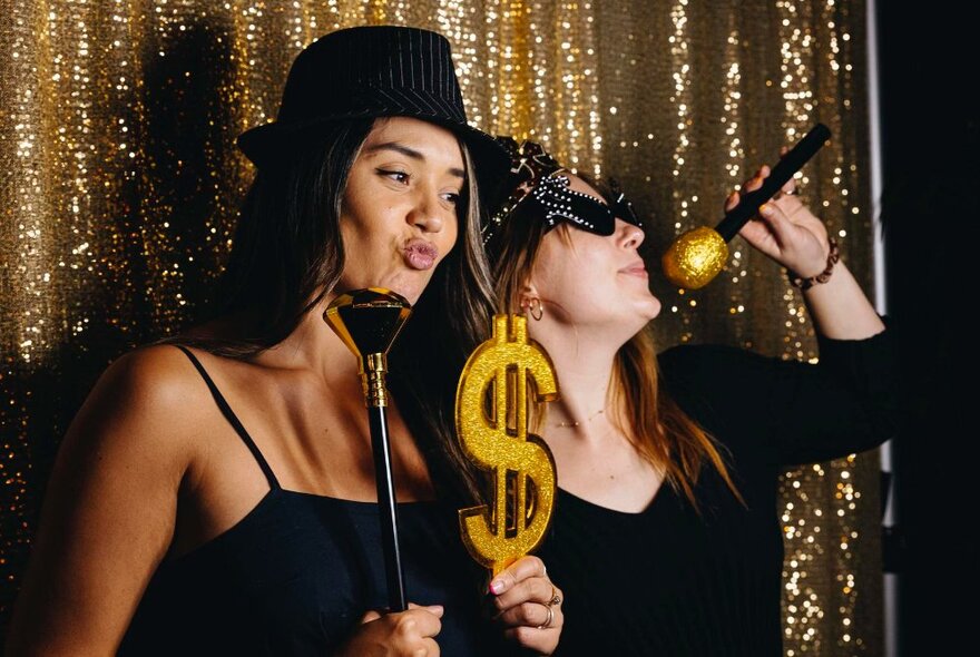 Two friends posing for photos in a photobooth.