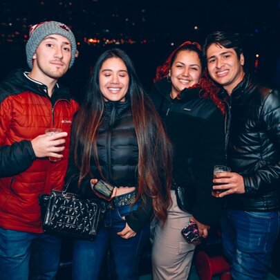 A group of four friends on the deck of a boat at night, smiling at the camera.